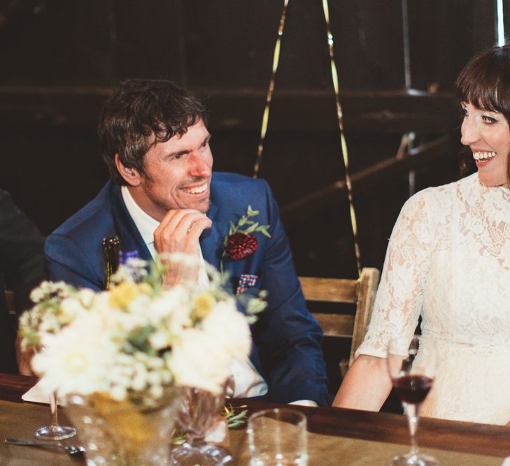 Bride in Lace Wedding Dress from Hope &amp; Harlequin and Groom in Navy Hugo Boss Suit  Laughing  at  the Top Table