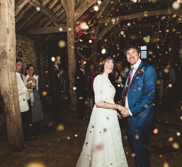 Confetti Bomb Moment with Bride in Lace Wedding Dress from Hope &amp; Harlequin and Groom in Navy Hugo Boss Suit