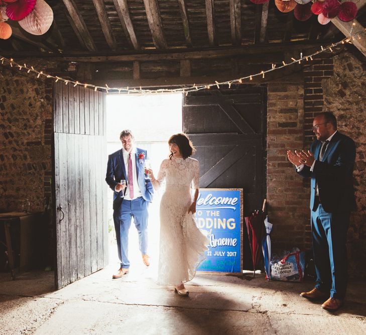 Bride in Lace Wedding Dress from Hope &amp; Harlequin and Groom in Navy Hugo Boss Suit Entering Barn Reception