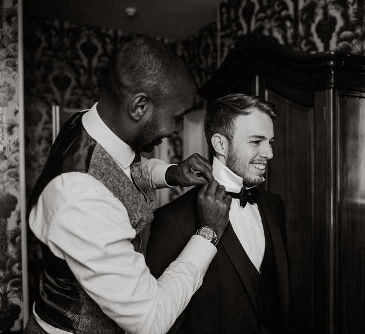 Groom putting on his bow tie on wedding morning