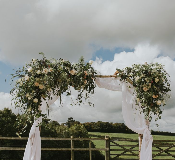 Floral Ceremony Arch With Drapes // Scottish Wedding With Ceilidh At Axnoller Dorset With Bohemian Styling Outdoor Wedding Ceremony With Images From Paul Underhill Dorset Wedding Photographer