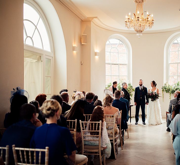 Bride in Charlie Brear Payton Bridal Gown &amp; Piora Feather Skirt and Groom in Three Piece Wool Suit