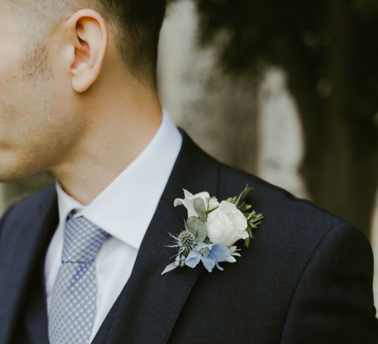 White flower buttonhole with blue suit and tie