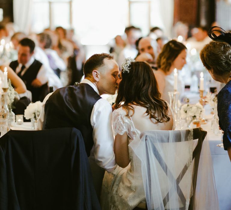 Bride and groom kiss during wedding breakfast