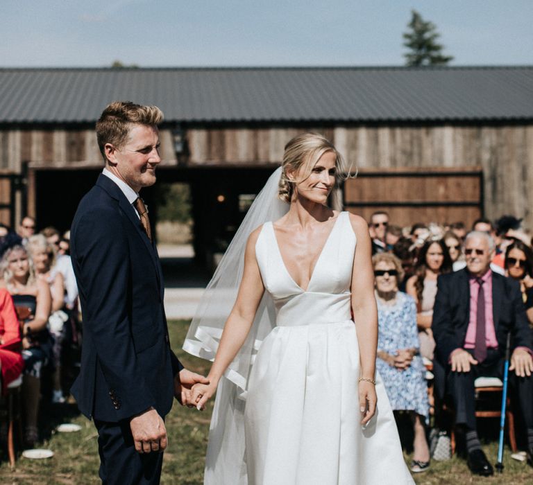 Bride in Jesus Peiro Wedding Dress and Groom in Dark Navy Suit at the Outdoor Wedding Ceremony Altar