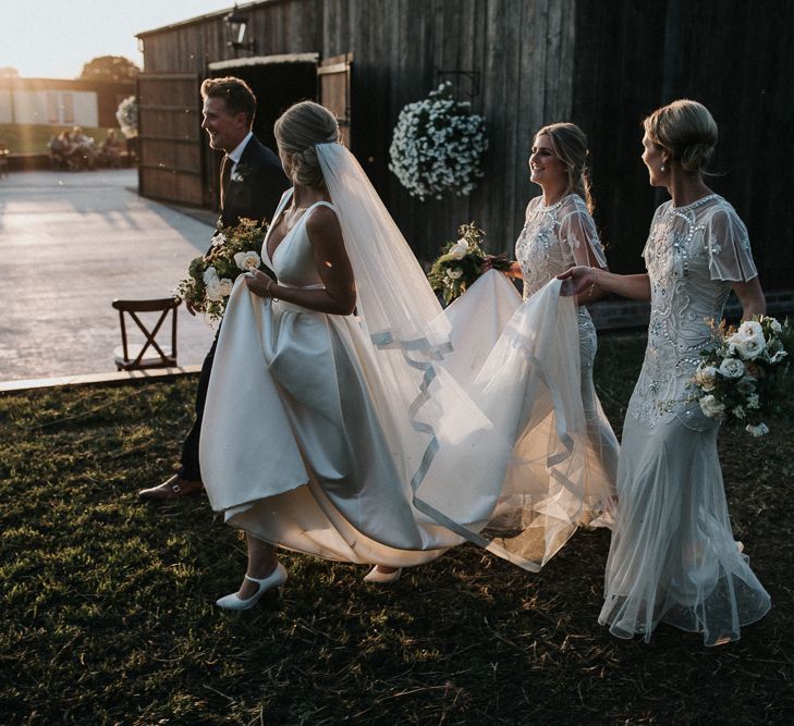 Bridesmaids in Embellished White Dresses Holding the Brides Jesus Peiro  Train Up