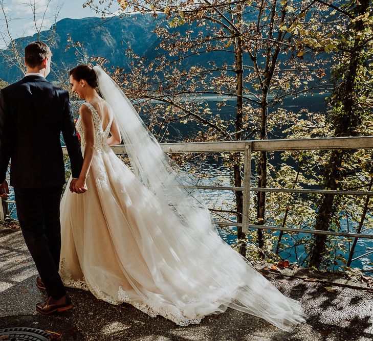 Bride in Lace and Tulle Princess Wedding Dress Walking Hand in Hand with Her Groom