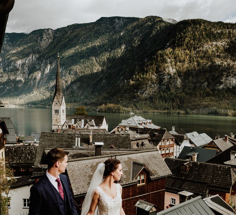 Bride and Groom Holding Hands with Rooftop Scenery of Hallstatt in Austria as the Backdrop