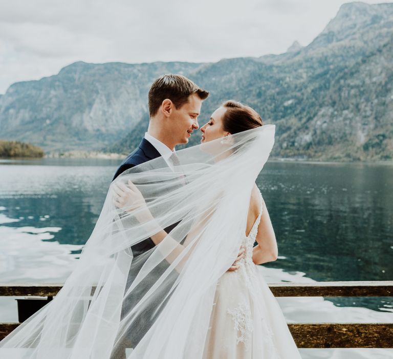 Bride and Groom Cuddling with Brides Veil Wrapped Around Them