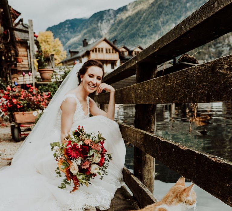 Bride Crouching Down in Her Lace Wedding Dress with a Ginger Cat