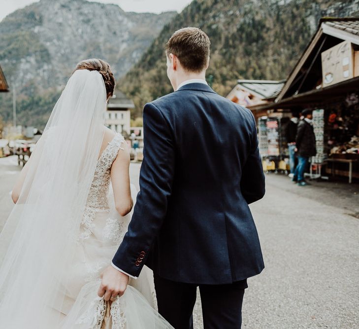 Groom Holding Up The Back of His Brides Lace Edged Wedding Dress