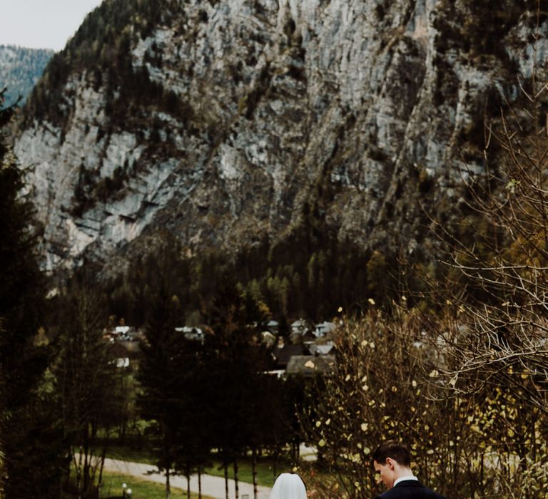 Groom Holding Up His Brides Wedding Dress as They Walk Down Some Steps