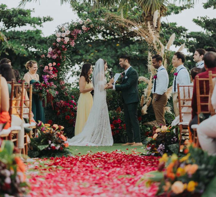 Bride and groom exchange vows in front of floral moon gate