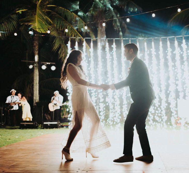 Bride and groom dance in front of wedding lights