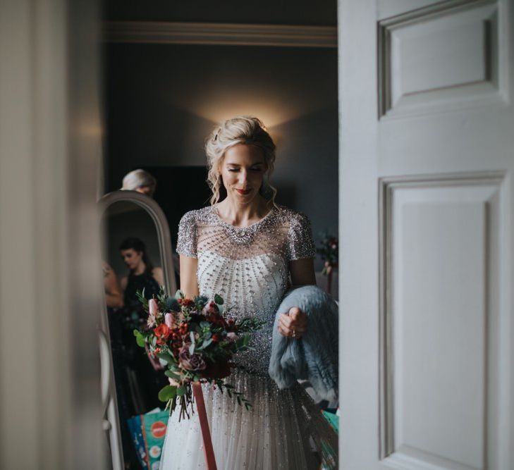 Bride wearing a beautiful embellished wedding dress with festive floral bouquet and a classic red lip