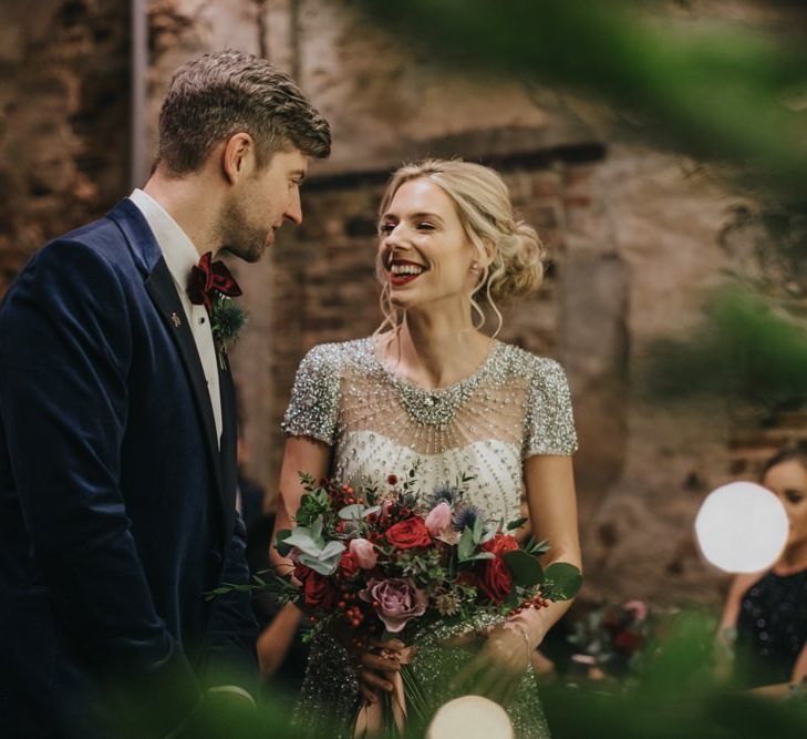 Bride and groom tie the knot at winter ceremony wearing a embellished wedding dress and navy velvet suit