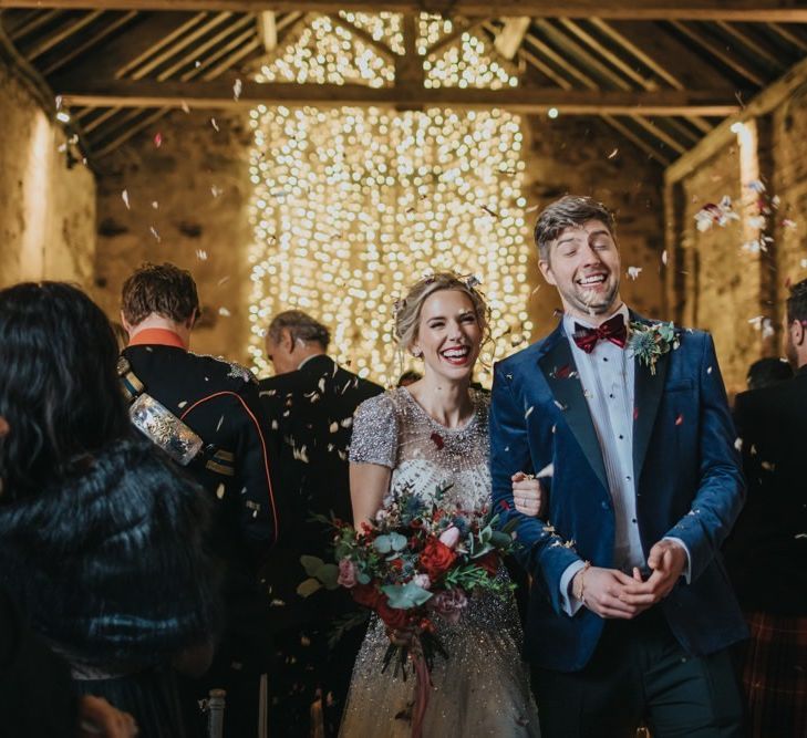 Confetti shot at winter wedding in a barn with fairy light curtain and embellished wedding dress