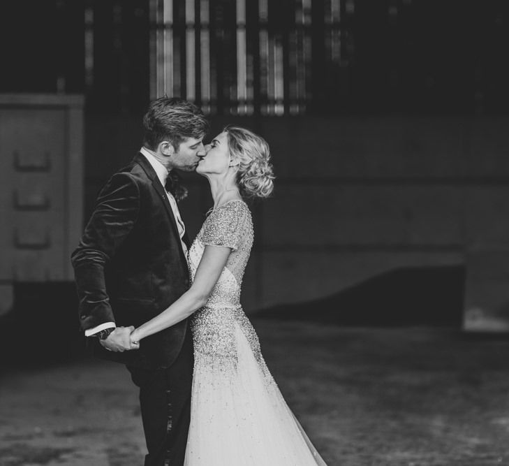 Bride and groom embrace at winter wedding wearing an embellished wedding dress and navy velvet suit