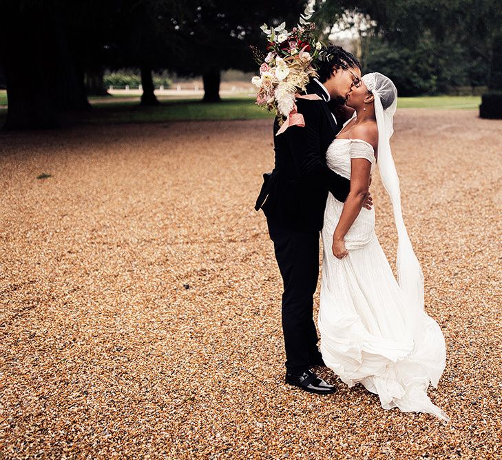 Black Bride in Juliet Cap Veil and Eliza Jane Howell Wedding Dress and Groom in Tuxedo Embracing