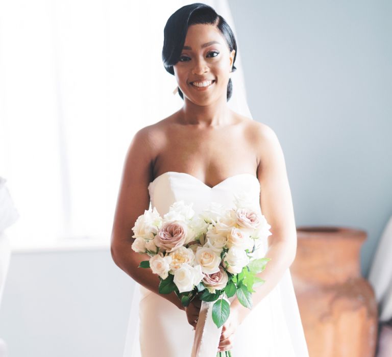 Bride in strapless Enzoani wedding dress holding her classic wedding bouquet