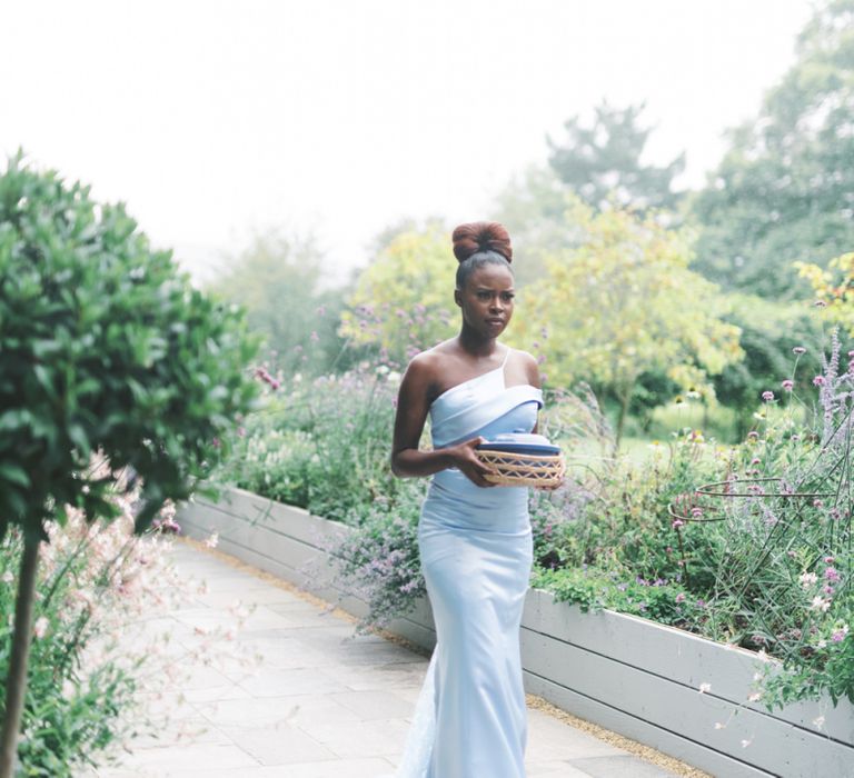 Bridesmaid in blue one shoulder dress holding a gift