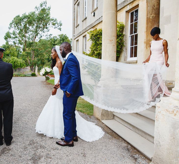 Bride in Lace Fishtail Gown with Strapless Sweetheart Neckline by Suzanne Neville | Lace Edged Cathedral Length Veil | Bridal Bouquet of White and Blush Roses and Peonies | Groomsman in Blue Three-Piece Ted Baker Suit | Mother of the Bride in Blush Pink Vera Wang Dress with Side Split | Silver Vintage Wedding Car | Peg Board Table Plan &amp; DIY Sweet Table for an Elmore Court Wedding | Mavric Photography