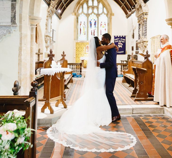 Bride in Lace Fishtail Gown with Strapless Sweetheart Neckline by Suzanne Neville | Lace Edged Cathedral Length Veil | Groom in Blue Three-Piece Ted Baker Suit with Blush Pink Tie | Wedding Ceremony at St John the Baptist Church, Elmore | Peg Board Table Plan &amp; DIY Sweet Table for an Elmore Court Wedding | Mavric Photography