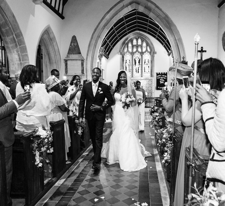 Bride in Lace Fishtail Gown with Strapless Sweetheart Neckline by Suzanne Neville | Lace Edged Cathedral Length Veil | Groom in Blue Three-Piece Ted Baker Suit with Blush Pink Tie | Bridal Bouquet of White and Blush Roses and Peonies | Wedding Ceremony at St John the Baptist Church, Elmore | Peg Board Table Plan &amp; DIY Sweet Table for an Elmore Court Wedding | Mavric Photography