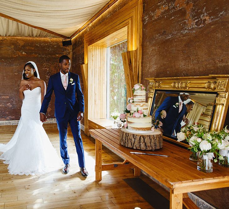 Bride in Lace Fishtail Gown with Strapless Sweetheart Neckline by Suzanne Neville | Lace Edged Cathedral Length Veil | Groom in Blue Three-Piece Ted Baker Suit with Blush Pink Tie | Three-Tier Semi-Naked Wedding Cake | Peg Board Table Plan &amp; DIY Sweet Table for an Elmore Court Wedding | Mavric Photography