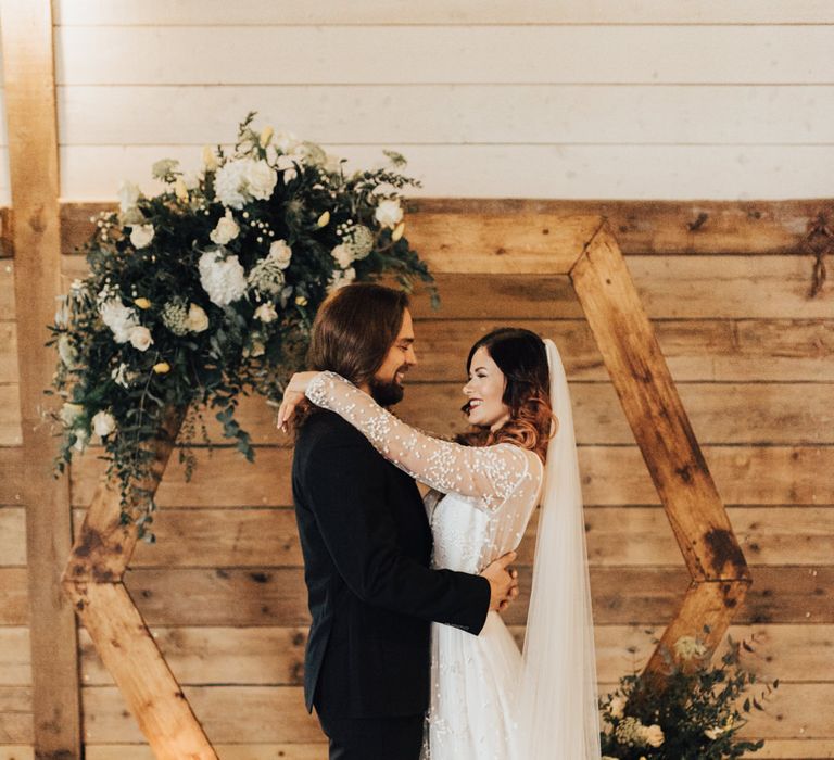 Boho Bride &amp; Long Haired Groom in Front of Hexagonal Moon Gate | Geometric Wedding Decor &amp; Styling by Locate to Create at The Cherry Barn | Rebecca Carpenter Photography