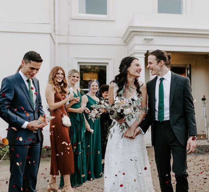 Bridesmaids in emerald green bridesmaid dresses throwing confetti