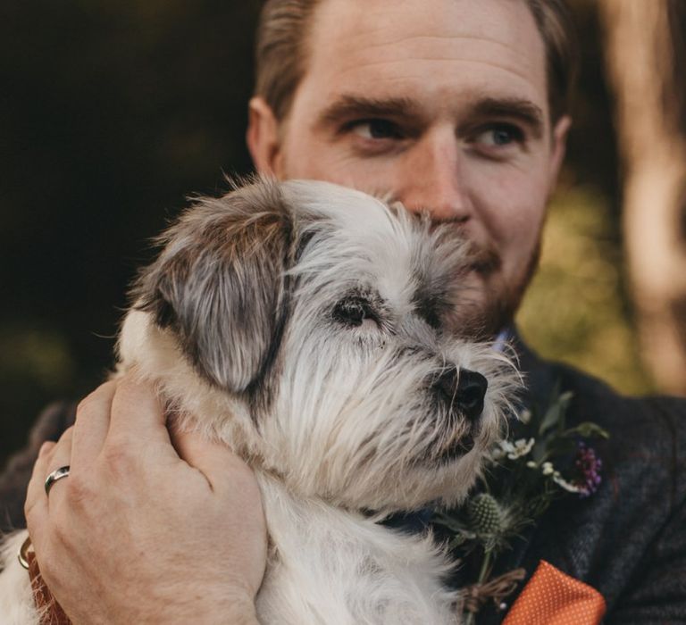 Groom in Grey Check Suit Hugging His Pet Dog