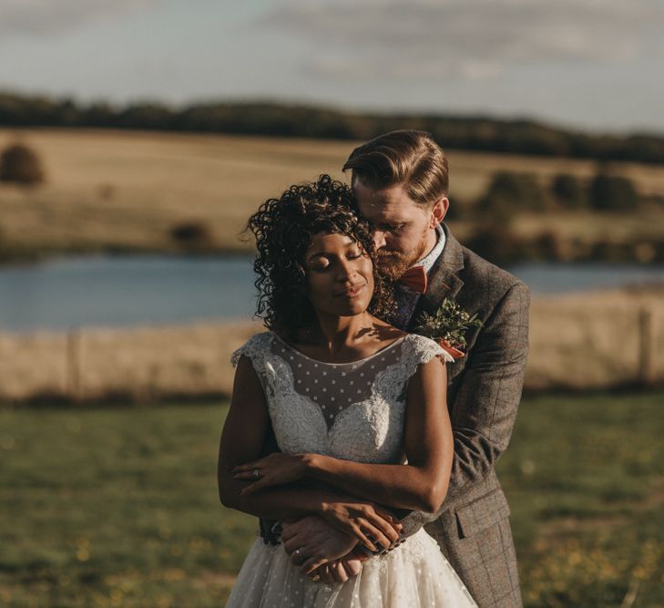 Groom in Grey Check Suit Embracing His Bride  in a Tulle Tea Length Wedding Dress