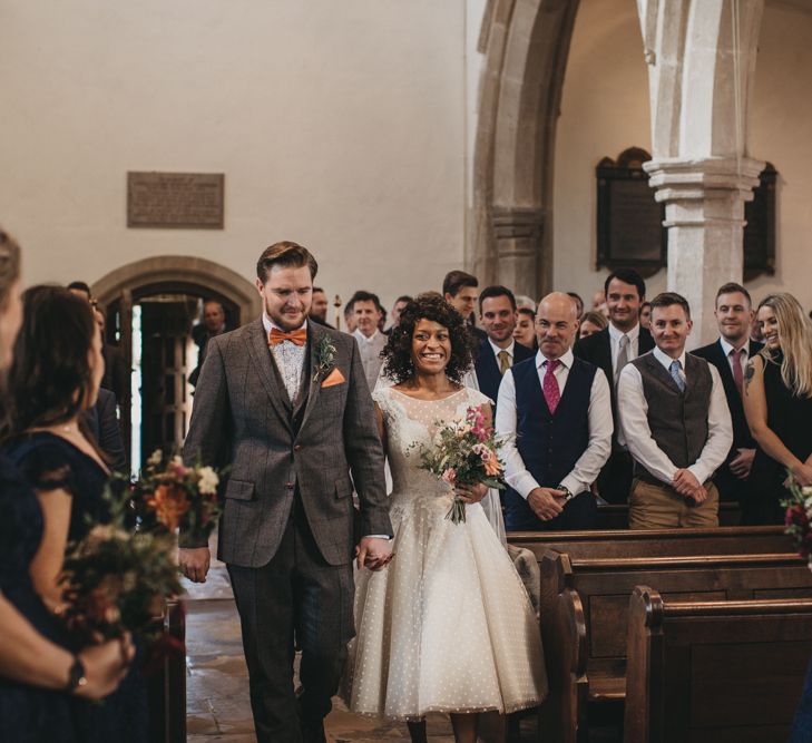 Church Wedding Ceremony with Bride in Tea Length Wedding Dress and Groom in Wool Suit Walking Up the Aisle