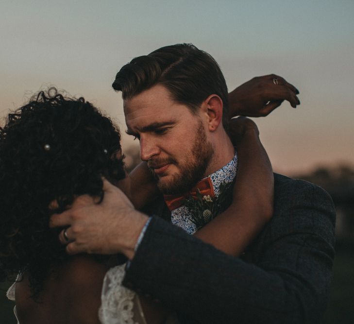 Groom in Floral Shirt and Bow Tie Embracing His Bride with Curly Hair