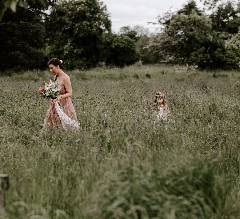 Bridesmaid and flower girl make their way to outdoor ceremony