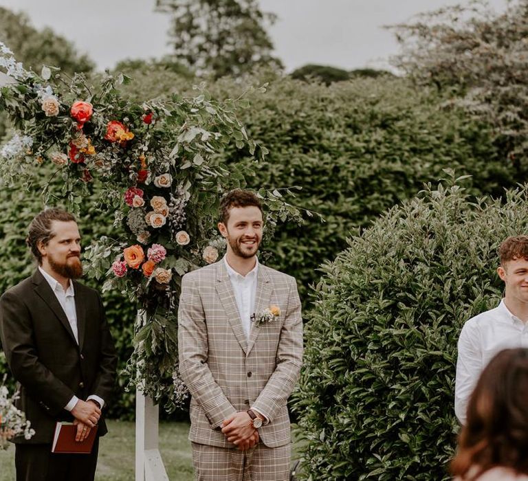 Groom sees bride walking down the aisle during outdoor ceremony