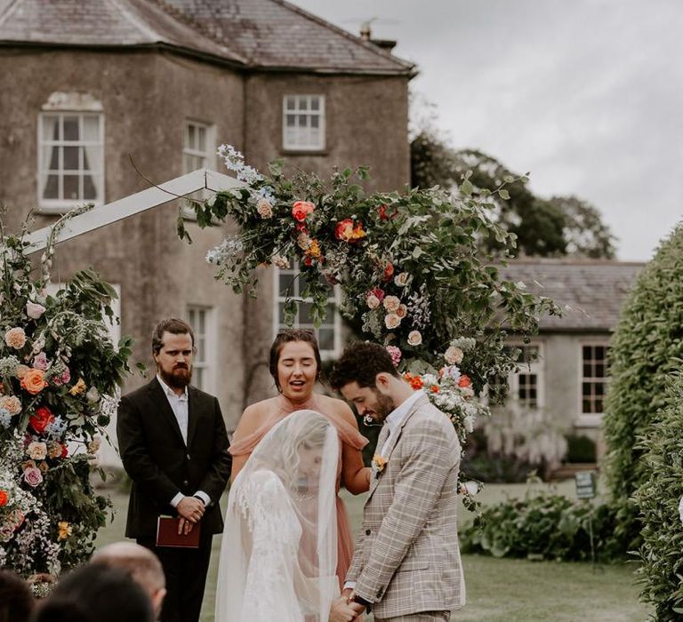 Bride and groom during wedding ceremony with flower arch