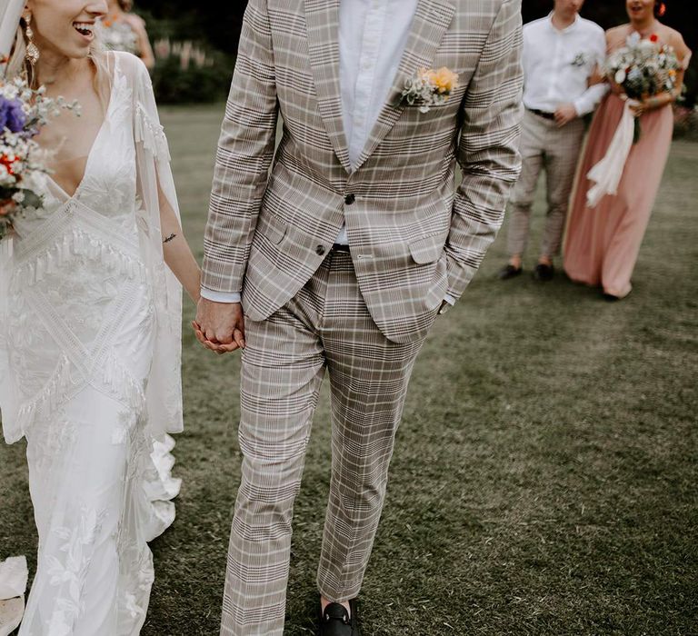 Cream wedding suit for groom at micro wedding with bride carrying wildflower bouquet