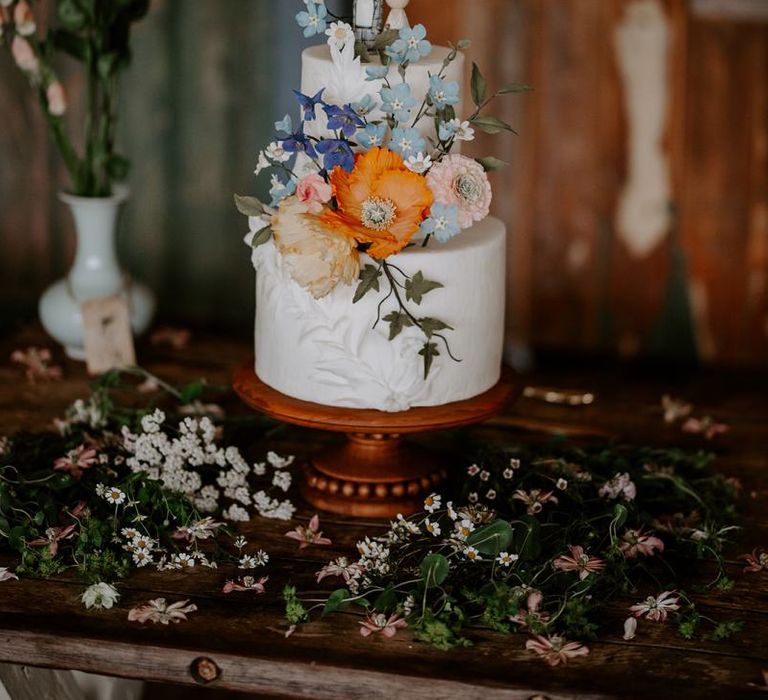 Wedding cake with wooden cake toppers and wildflower decor