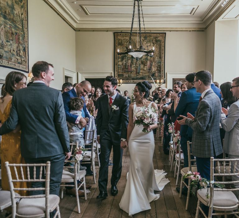 Bride in Pronovias Wedding Dress and Groom in Cad &amp; The Dandy Suit Walking Up the Aisle as Husband &amp; Wife