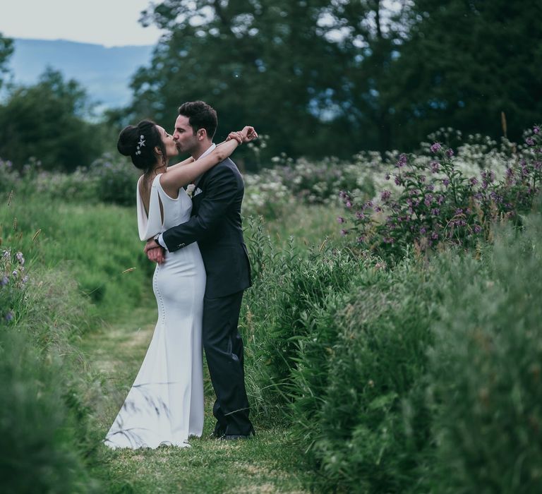 Bride in Fitted Pronovias Wedding Dress with Cowl Back Detail and Groom in Cad &amp; The Dandy Suit Embracing