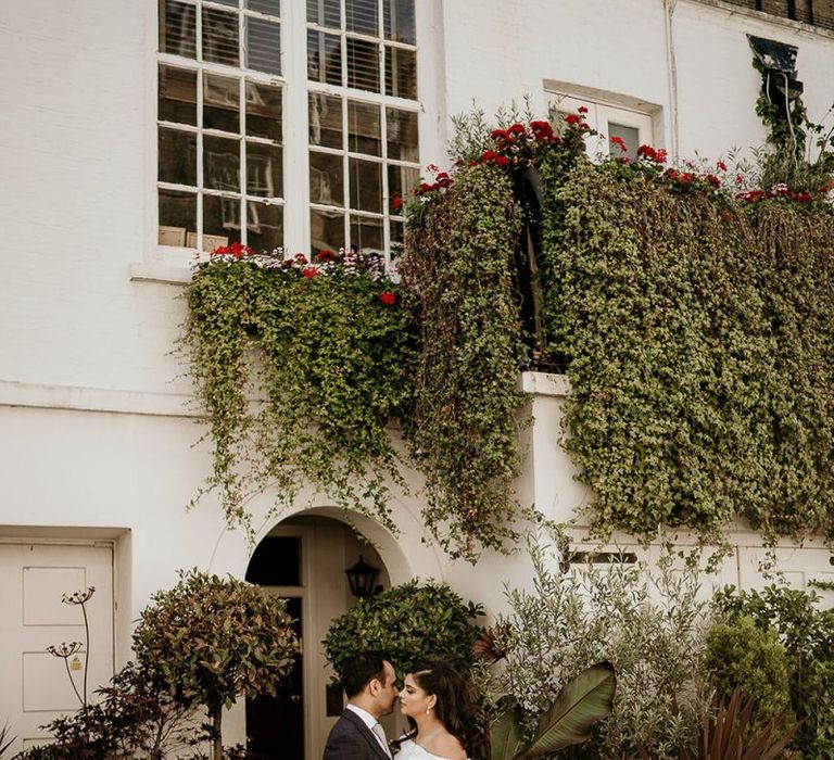 Bride and groom portrait in front of a plant covered building