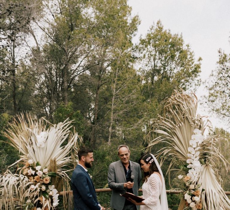 Bride in Margaux Tardits Wedding Dress  and Groom in a Navy Wedding Suit Exchanging Vows