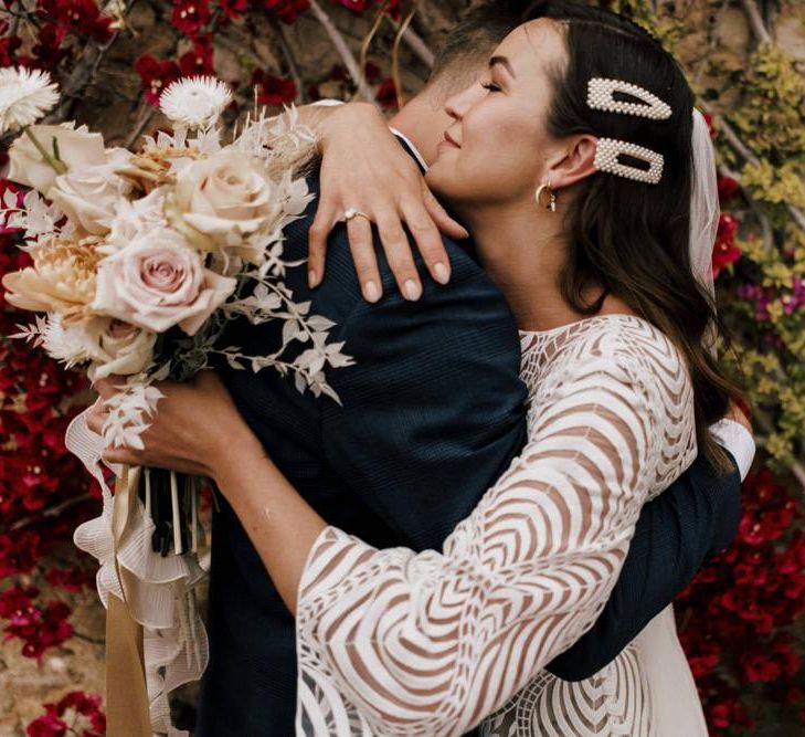 Bride in Margaux Tardits Wedding Dress  with Swirl Pattern and Bell Sleeves Embracing Her Husband