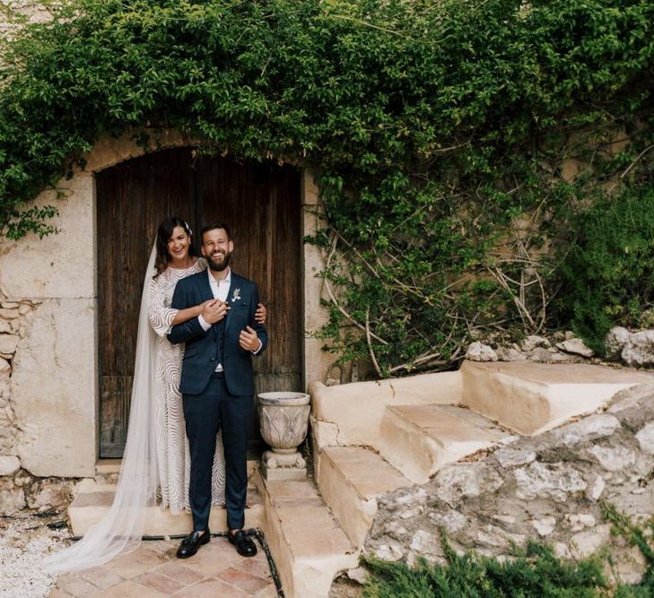 Bride in Margaux Tardits Wedding Dress with Embracing Her Husband in a Moss Bros. Check Wedding Suit