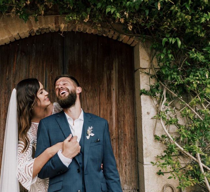 Groom in Navy check Moss Bros. Wedding Suit and Bride in Margaux Tardits Wedding Dress Laughing