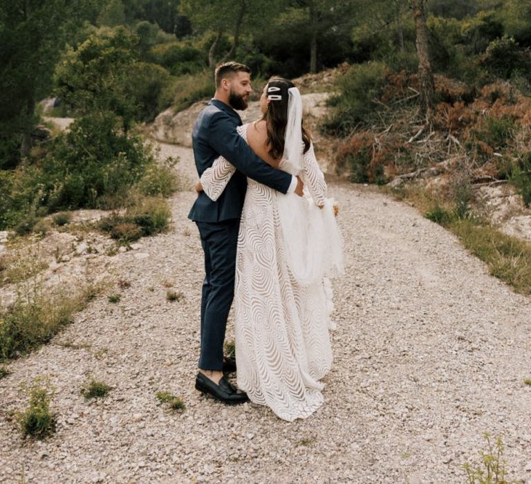 Bride in Margaux Tardits Wedding Dress and Groom in Navy Wedding Suit Embracing