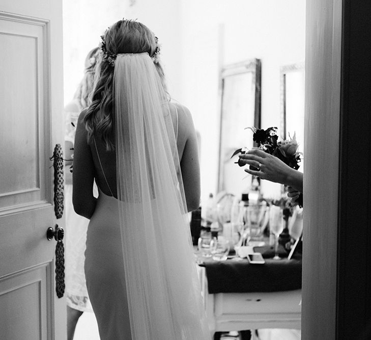 Black and White Portrait of Bride Standing in the Doorway Showing off Her Cathedral Length Veil