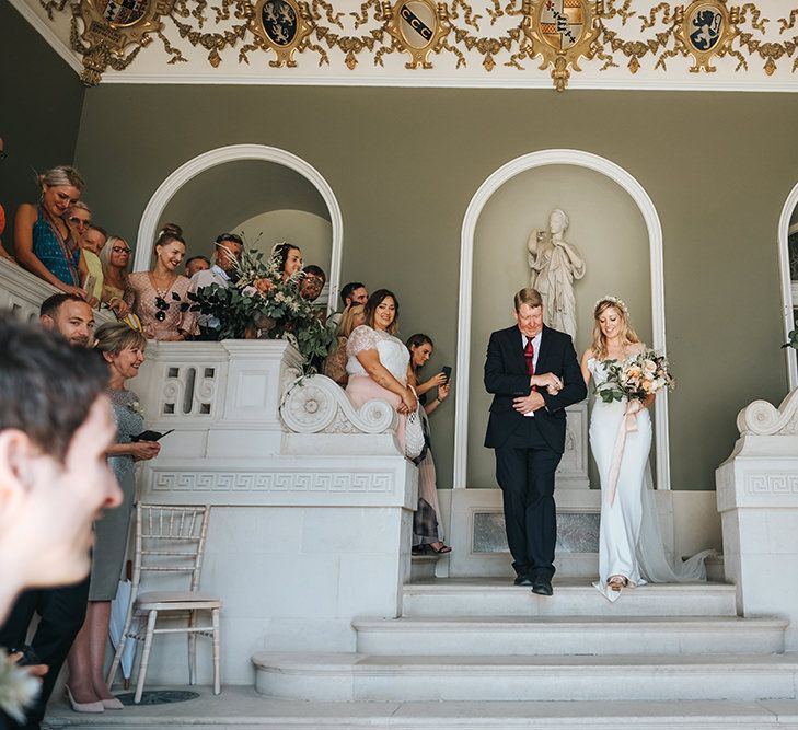 Bride in Fitted Savannah Miller Chloe Wedding Dress and Flower Crown Escorted Down the Aisle by her Father